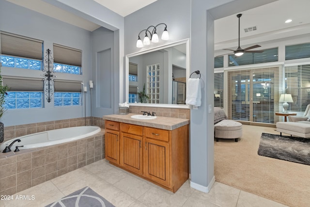 bathroom featuring vanity, a relaxing tiled tub, tile patterned floors, and ceiling fan