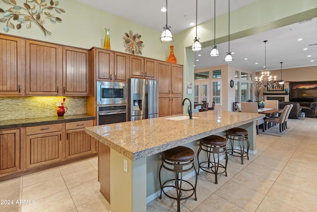 kitchen with an island with sink, sink, a breakfast bar area, hanging light fixtures, and stainless steel appliances