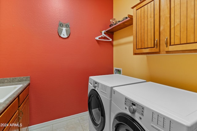 washroom with cabinets, washing machine and dryer, and sink