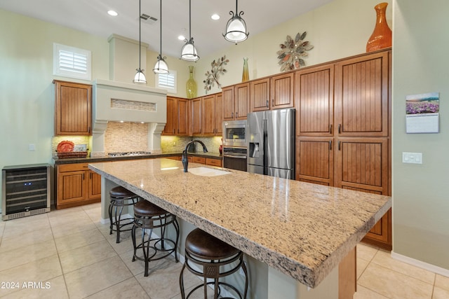 kitchen with wine cooler, a spacious island, sink, hanging light fixtures, and appliances with stainless steel finishes