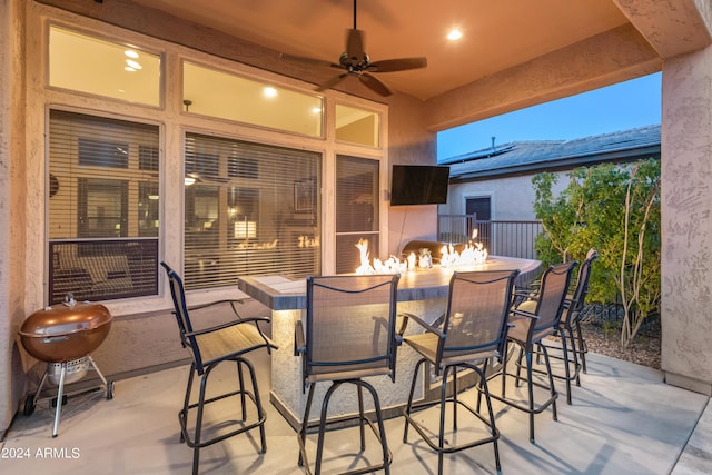 view of patio with an outdoor bar, ceiling fan, and a fire pit