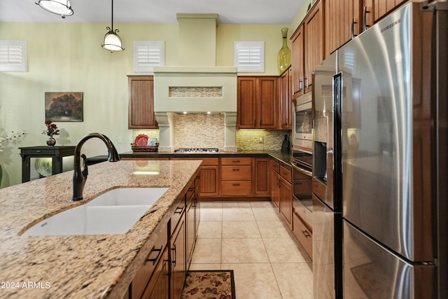 kitchen featuring sink, light tile patterned floors, appliances with stainless steel finishes, pendant lighting, and light stone countertops