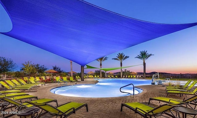 pool at dusk featuring a patio