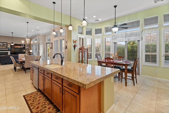 kitchen with sink, light stone counters, decorative light fixtures, a center island with sink, and light tile patterned floors