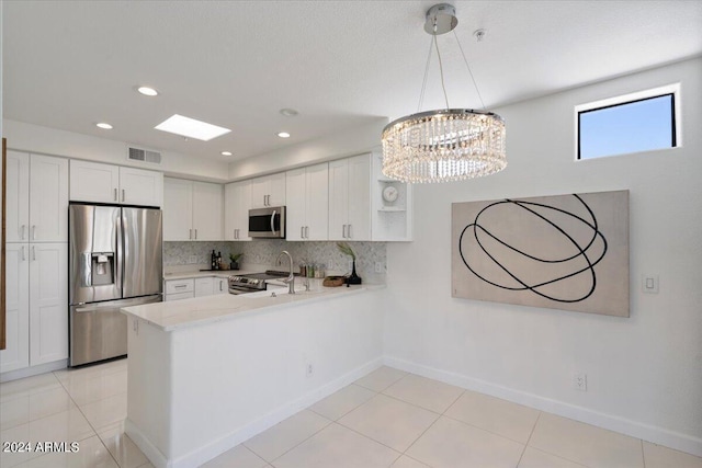 7222 E Gainey Ranch Rd Unit 241, Scottsdale, AZ 85258 - kitchen with appliances with stainless steel finishes, a peninsula, white cabinets, decorative backsplash, and baseboards