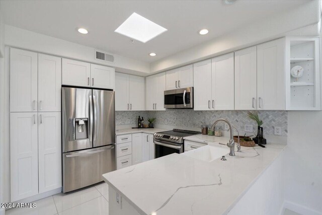 7222 E Gainey Ranch Rd Unit 241, Scottsdale, AZ 85258 - kitchen featuring stainless steel appliances, a sink, a skylight, white cabinets, and recessed lighting