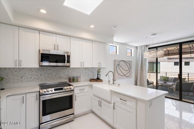 7222 E Gainey Ranch Rd Unit 241, Scottsdale, AZ 85258 - kitchen featuring stainless steel appliances, a sink, light tile patterned floors, a peninsula, and backsplash