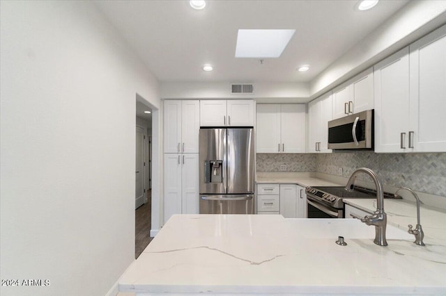 7222 E Gainey Ranch Rd Unit 241, Scottsdale, AZ 85258 - kitchen with stainless steel appliances, light stone countertops, white cabinets, recessed lighting, and backsplash
