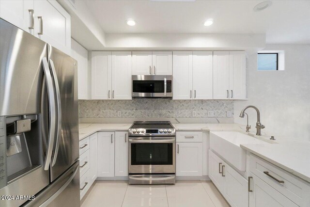 7222 E Gainey Ranch Rd Unit 241, Scottsdale, AZ 85258 - kitchen with stainless steel appliances, a sink, white cabinets, decorative backsplash, and light stone counters
