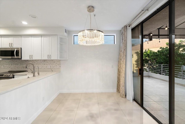 7222 E Gainey Ranch Rd Unit 241, Scottsdale, AZ 85258 - kitchen with appliances with stainless steel finishes, a chandelier, light stone counters, white cabinetry, and tasteful backsplash