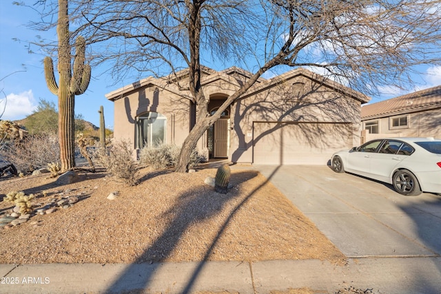 view of front of house featuring an attached garage, a tiled roof, concrete driveway, and stucco siding