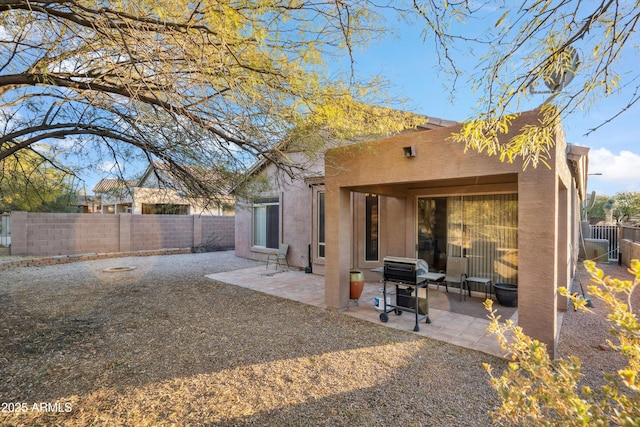 rear view of property featuring a patio area, a fenced backyard, and stucco siding