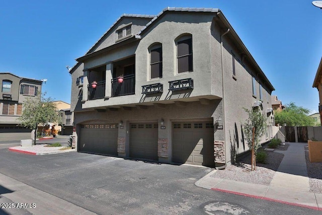 view of front of home featuring stucco siding, a garage, and a balcony
