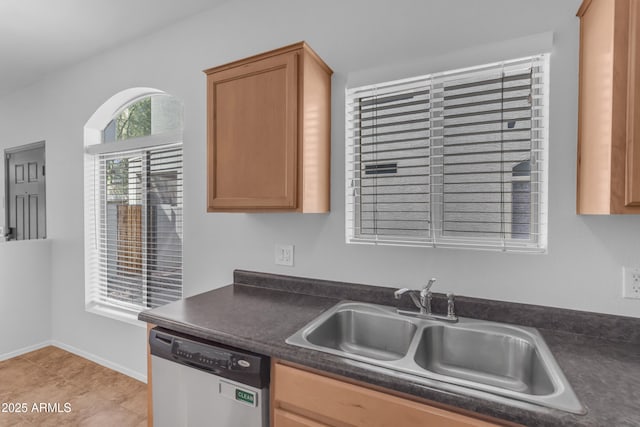 kitchen featuring dishwasher, a sink, dark countertops, baseboards, and light tile patterned floors
