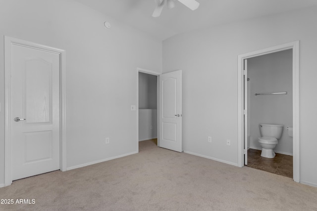 unfurnished bedroom with carpet, vaulted ceiling, ensuite bathroom, baseboards, and ceiling fan