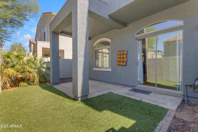 view of exterior entry featuring stucco siding and a patio area