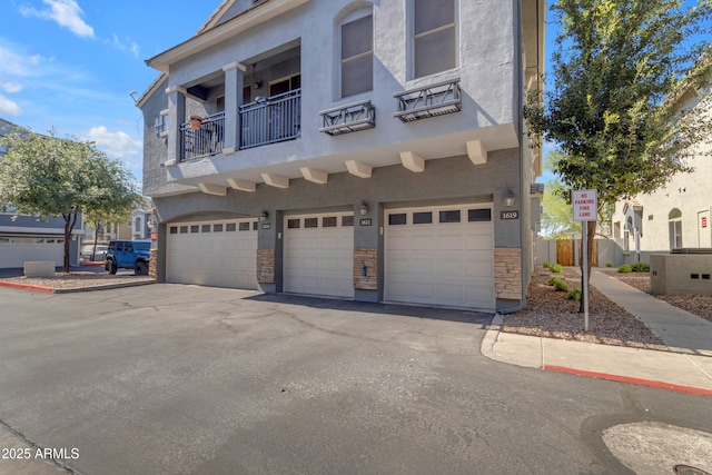 view of front of home featuring an attached garage, driveway, and a balcony