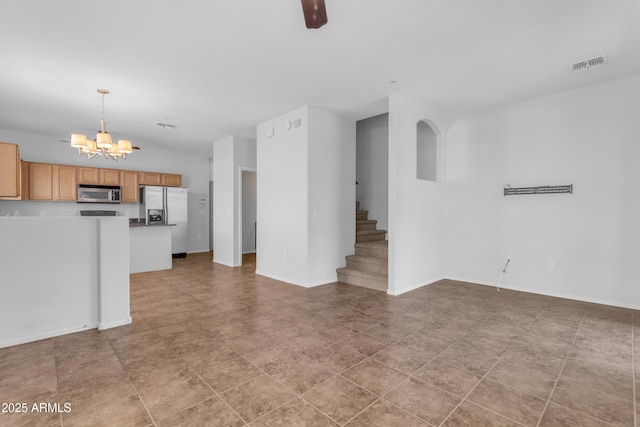 unfurnished living room featuring a chandelier, stairway, and baseboards