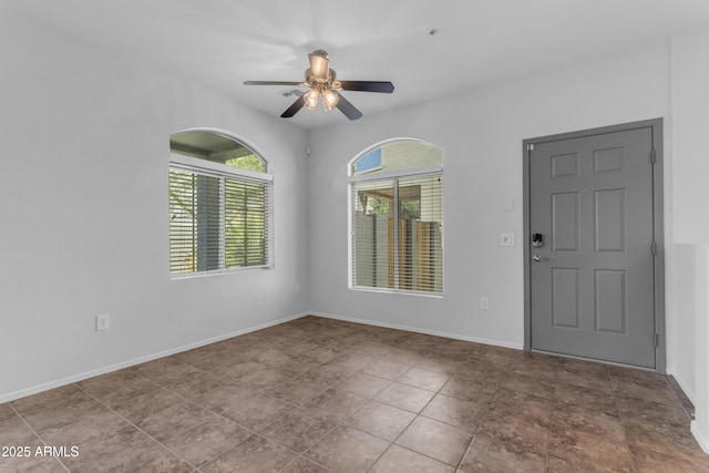 spare room with ceiling fan and baseboards