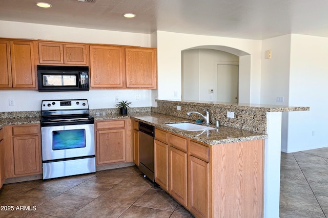 kitchen with stainless steel appliances, a peninsula, a sink, backsplash, and dark stone counters