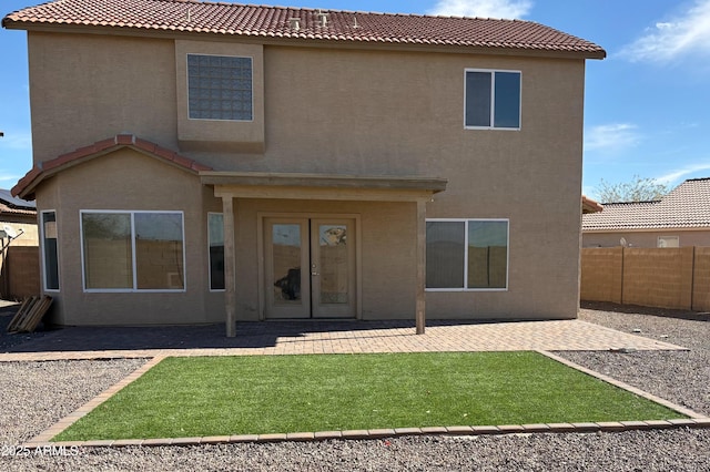 rear view of property with a lawn, a tile roof, fence, a patio area, and stucco siding