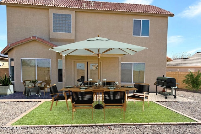 rear view of house featuring a tile roof, a patio area, fence, and stucco siding