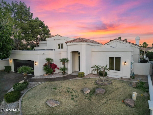 mediterranean / spanish-style home with a garage, driveway, fence, and stucco siding