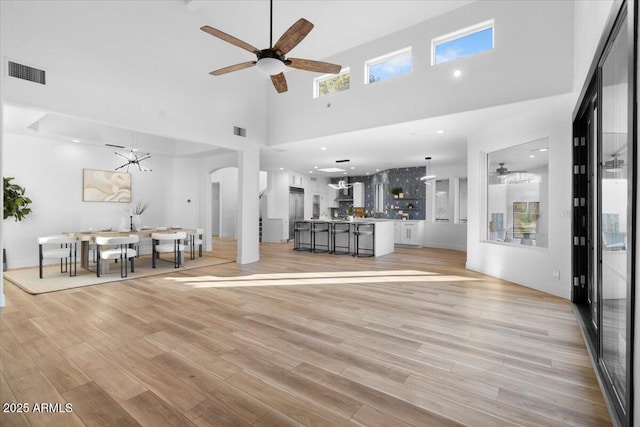 unfurnished living room featuring light wood-style floors, arched walkways, and visible vents