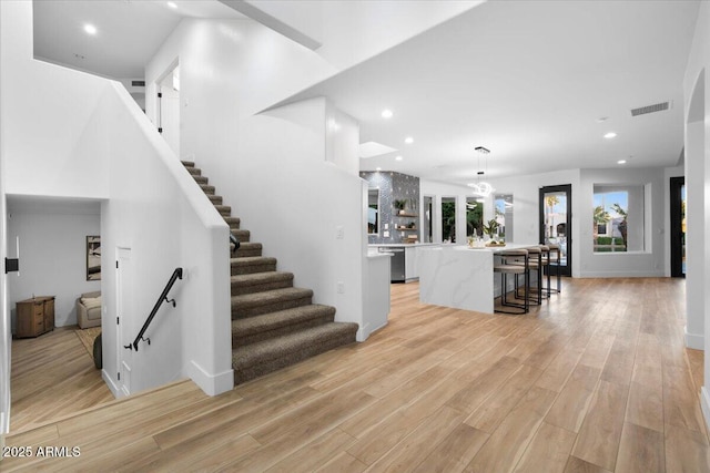 interior space featuring light wood-style floors, recessed lighting, visible vents, and stairs