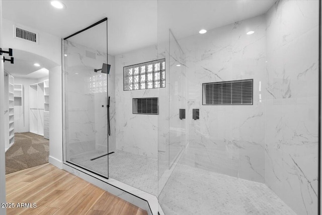 bathroom with a marble finish shower, wood finished floors, visible vents, and recessed lighting