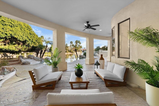 view of patio with a water view, an outdoor hangout area, and a ceiling fan