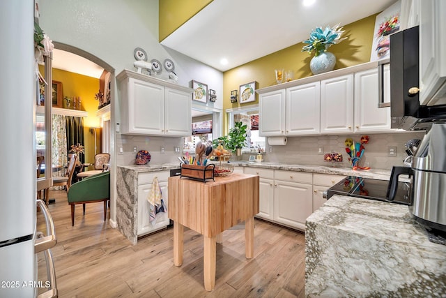 kitchen featuring tasteful backsplash, light stone countertops, white cabinets, and light hardwood / wood-style floors