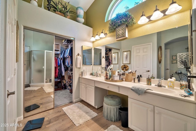 bathroom featuring vanity, an enclosed shower, wood-type flooring, and a high ceiling