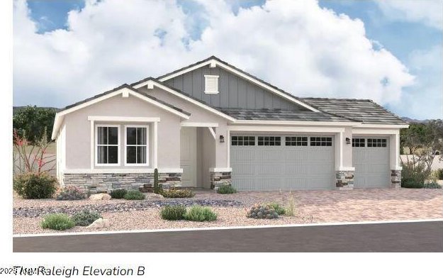 craftsman-style home with stone siding, an attached garage, board and batten siding, and driveway