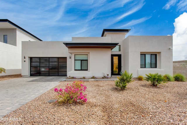 contemporary home with a garage, stucco siding, and decorative driveway