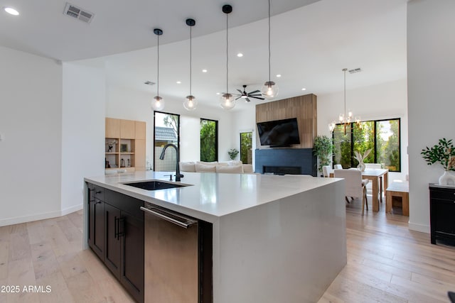 kitchen with a sink, a fireplace, light countertops, recessed lighting, and visible vents
