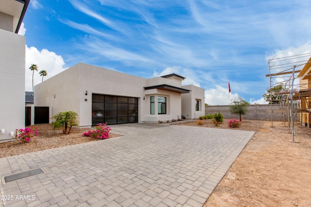 view of side of property featuring a garage, fence, stucco siding, and decorative driveway