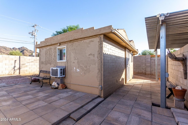 view of side of property with a patio and a wall unit AC