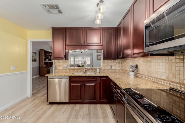 kitchen featuring sink, light wood-type flooring, stainless steel appliances, and light stone countertops