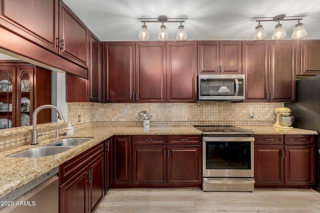 kitchen with sink, light hardwood / wood-style flooring, stainless steel appliances, tasteful backsplash, and light stone countertops