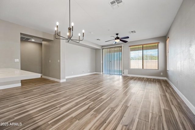 unfurnished living room featuring baseboards, visible vents, ceiling fan with notable chandelier, and light wood-style floors