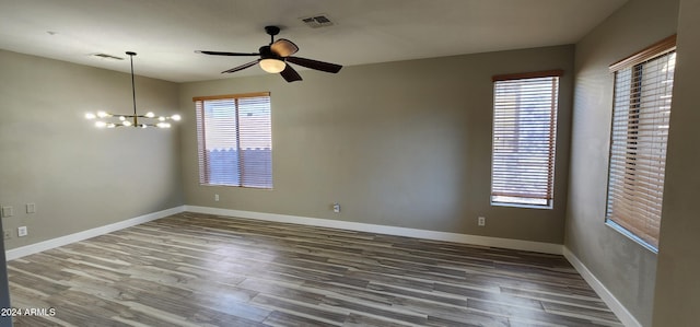 spare room featuring dark hardwood / wood-style floors and ceiling fan with notable chandelier