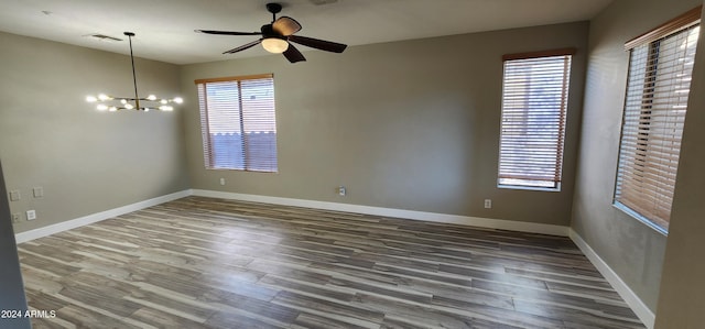 empty room with hardwood / wood-style flooring and ceiling fan with notable chandelier