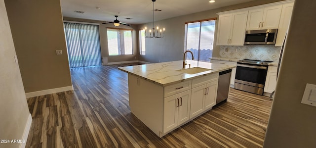 kitchen featuring appliances with stainless steel finishes, white cabinetry, a center island with sink, and a wealth of natural light