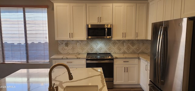 kitchen featuring white cabinetry, stainless steel appliances, and light stone countertops