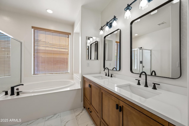 bathroom with a garden tub, a stall shower, marble finish floor, and a sink