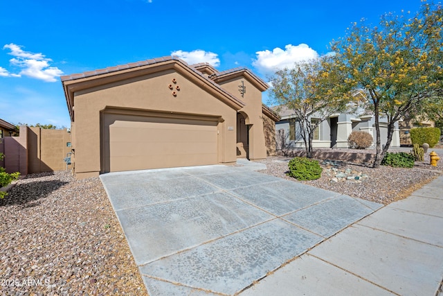 view of front of home featuring concrete driveway, a tile roof, a gate, an attached garage, and stucco siding
