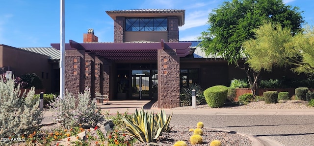 view of front of property featuring a standing seam roof, metal roof, stone siding, a chimney, and french doors