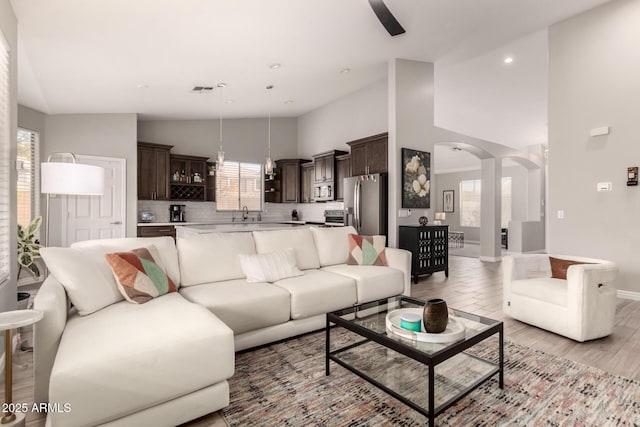 living room with plenty of natural light, light wood-type flooring, and high vaulted ceiling