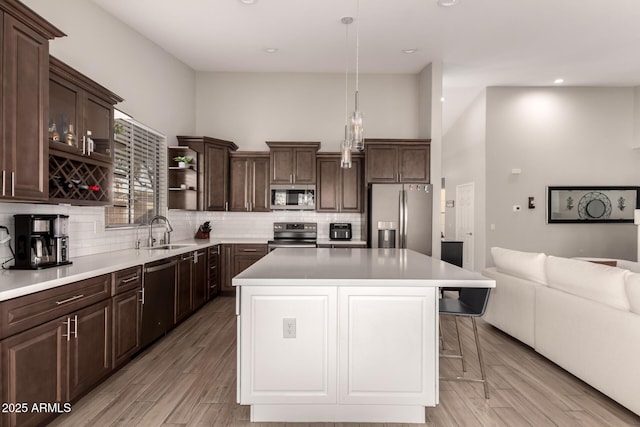 kitchen with sink, hanging light fixtures, stainless steel appliances, and a kitchen island